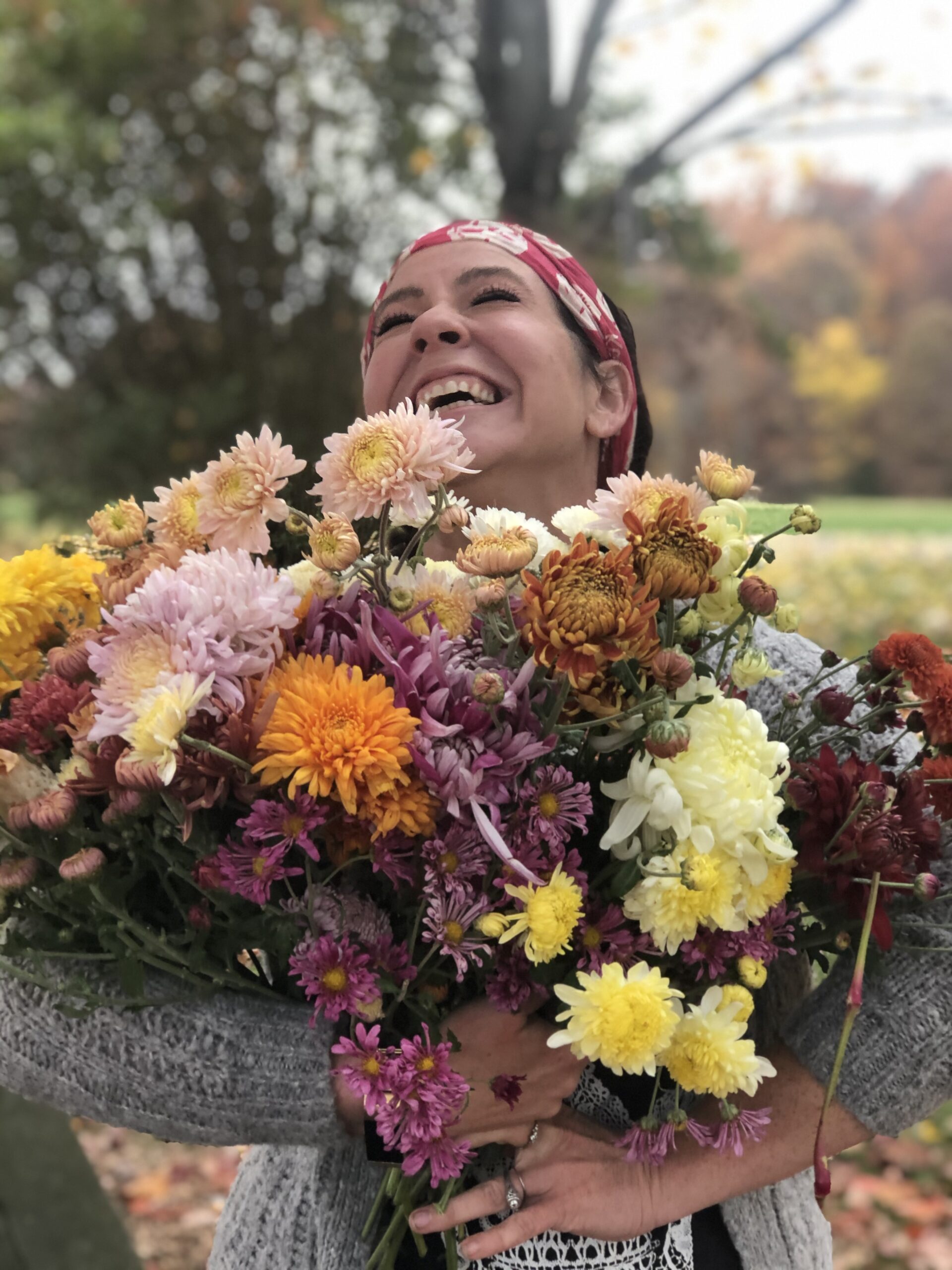 Woman holding bunches of colorful fall chrysanthemums.